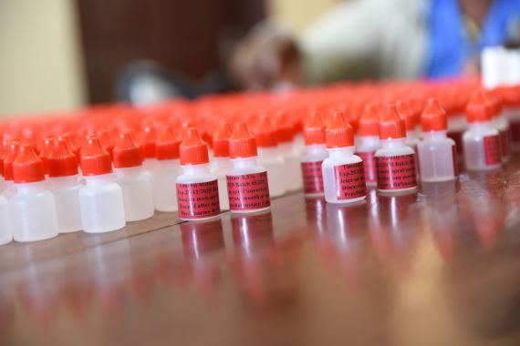 Unzählige kleine Plastikfläschchen mit rotem Schraubdeckel, teils mit, teils ohne Etikett