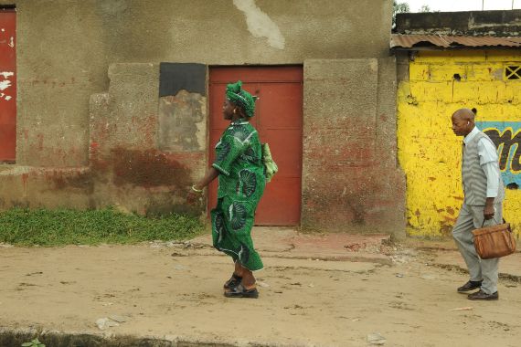 Eine Frau und ein Mann laufen eine unbefestigte Straße in Kinshasa entlang.