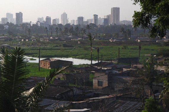 Die tansanische Hauptstadt Daressalam. Im Hintergrund die Skyline mit modernen Wolkenkratzern, im Vordergrund einfache kleine Hütten.
