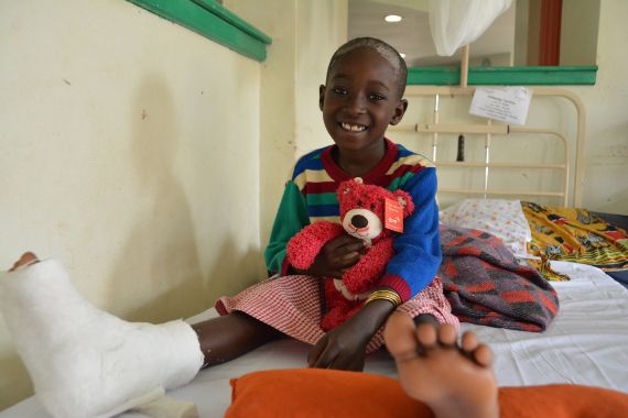 Afrikanisches Kind mit Gips am Bein sitzt im Krankenhausbett