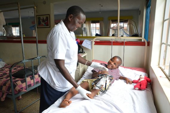 Afrikanisches Kind liegt mit Beinschiene im Krankenhausbett