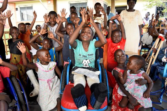 Lachende und winkende Kinder mit und ohne Rollstuhl