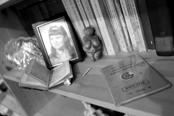 Gerahmtes Foto eines Mädchens in einem Bücherregal, daneben eine kleine Frauenfigur, ein Pass des deutschen Judo-Bunds sowie eine Schraube.