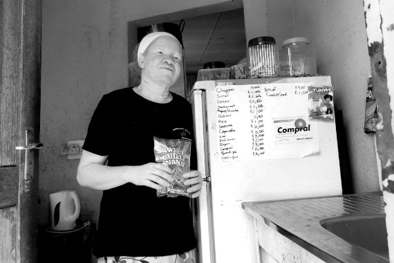 Eine Frau mit langem, dunklem Haar legt ihre Hände auf eine nasse Scheibe, hinter der sie steht.