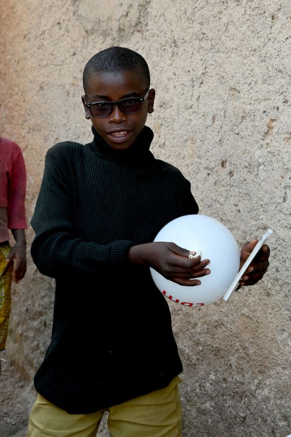 Ein junger Mann hält einen Luftballon in Händen.