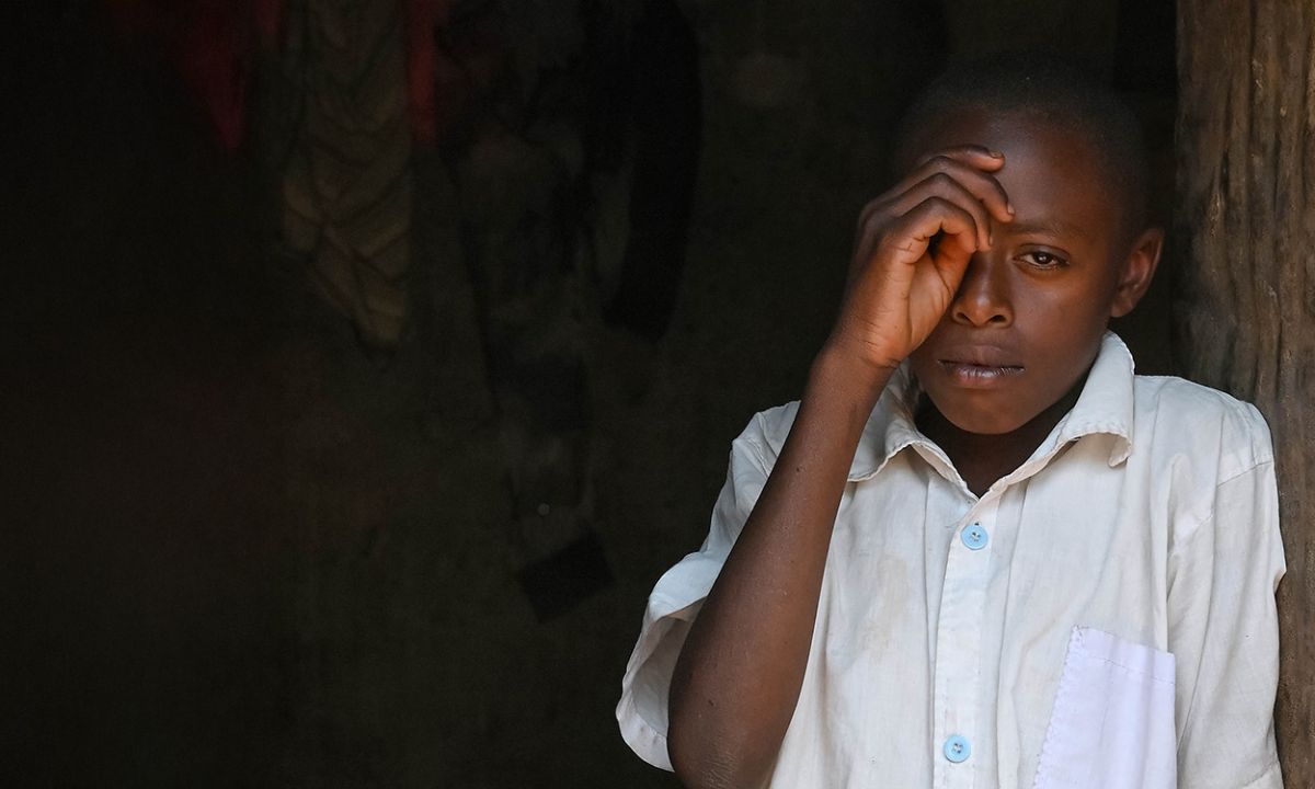 Ein etwa elfjähriger Junge lehnt sich an eine Wand und hält eine Hand vors linke Auge.