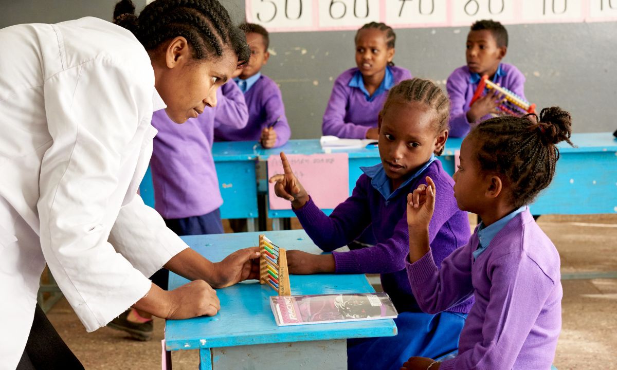 Eine Frau und zwei kleine Mädchen im Klassenhzimmer sprechen miteinander in Gebärdensprache.