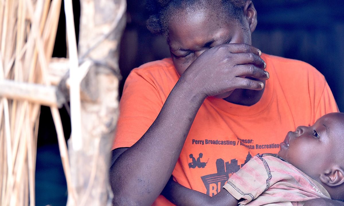 Eine Frau in einem Raum mit braunen Lehmwänden hat rote, entzündete Augen.