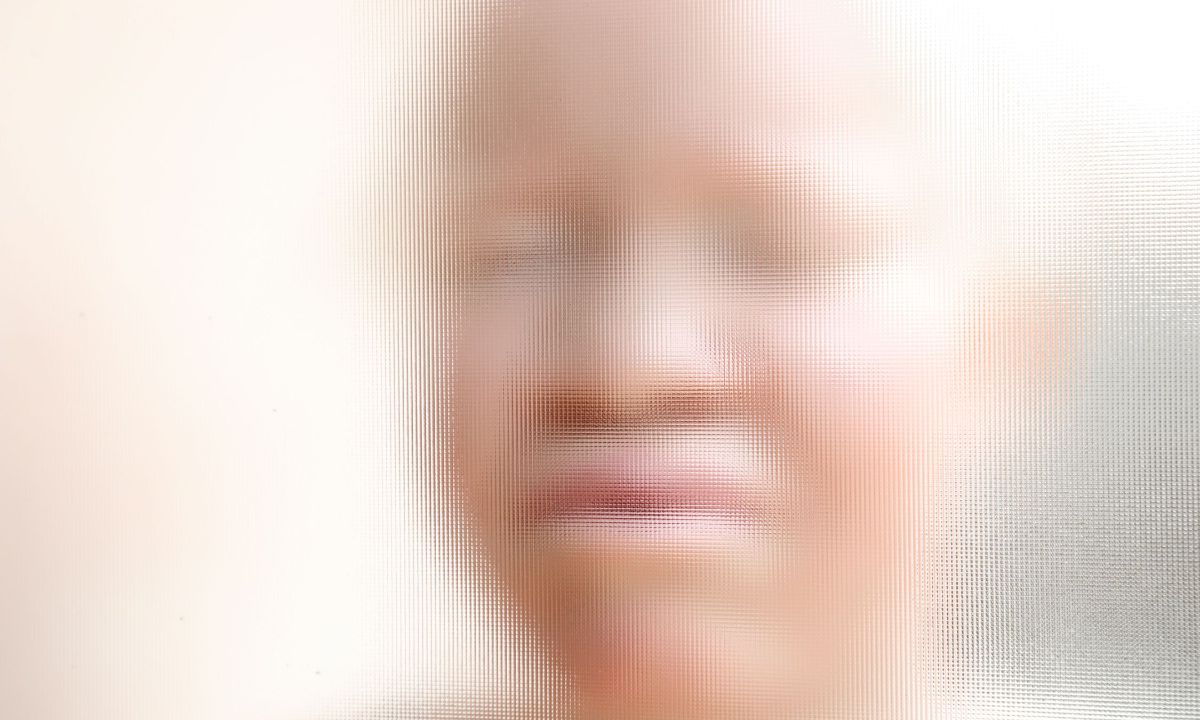 Gesicht einer hellhäutigen afrikanischen Frau hinter einer Strukturglasscheibe