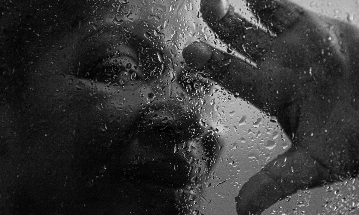 Gesicht einer Frau aus Lateinamerika hinter einer Glasscheibe, an die sie mit der Hand fasst